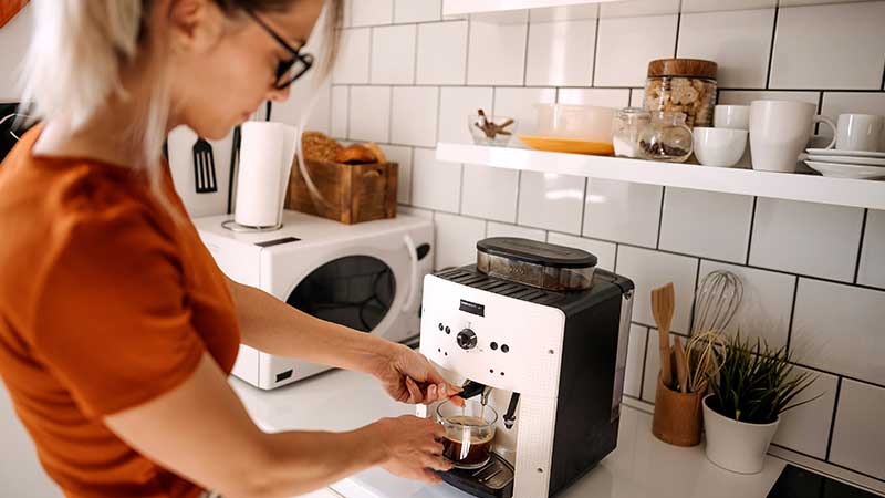 mulher a tirar café em máquina de café automática
